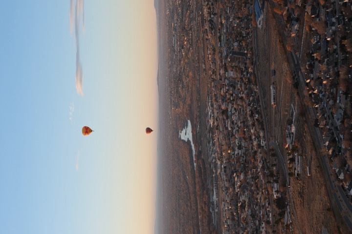 Hot-air balloons drifting over a desert town at dawn