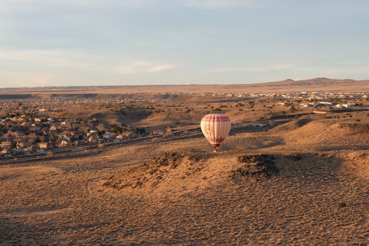 Lone balloon descending over high-desert scrub