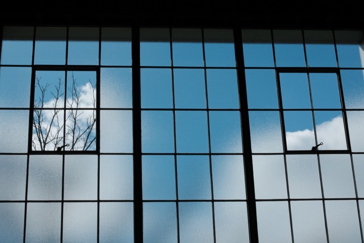 Sky and clouds beyond a tall factory window grid