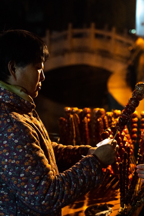 Vendor preparing candied haws on a night street