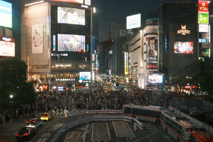 Crowds streaming across Shibuya Crossing at night
