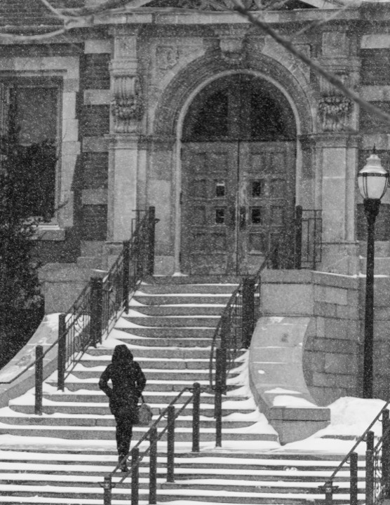 A lone figure climbing snow-covered library steps