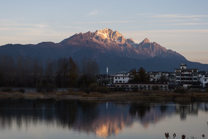 Snow-capped peak catching first light above a still lake